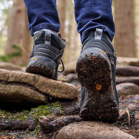a close up shot of a man's hiking boots while he walks up some rocks