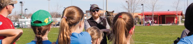 a raptor handler holds an owl for a group of kids to see