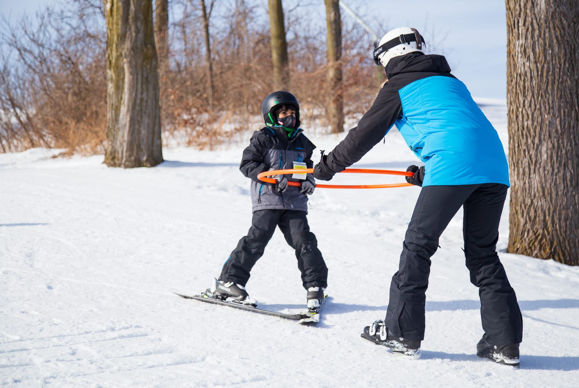 ski instructor pulling a young child forward on a pair of skis