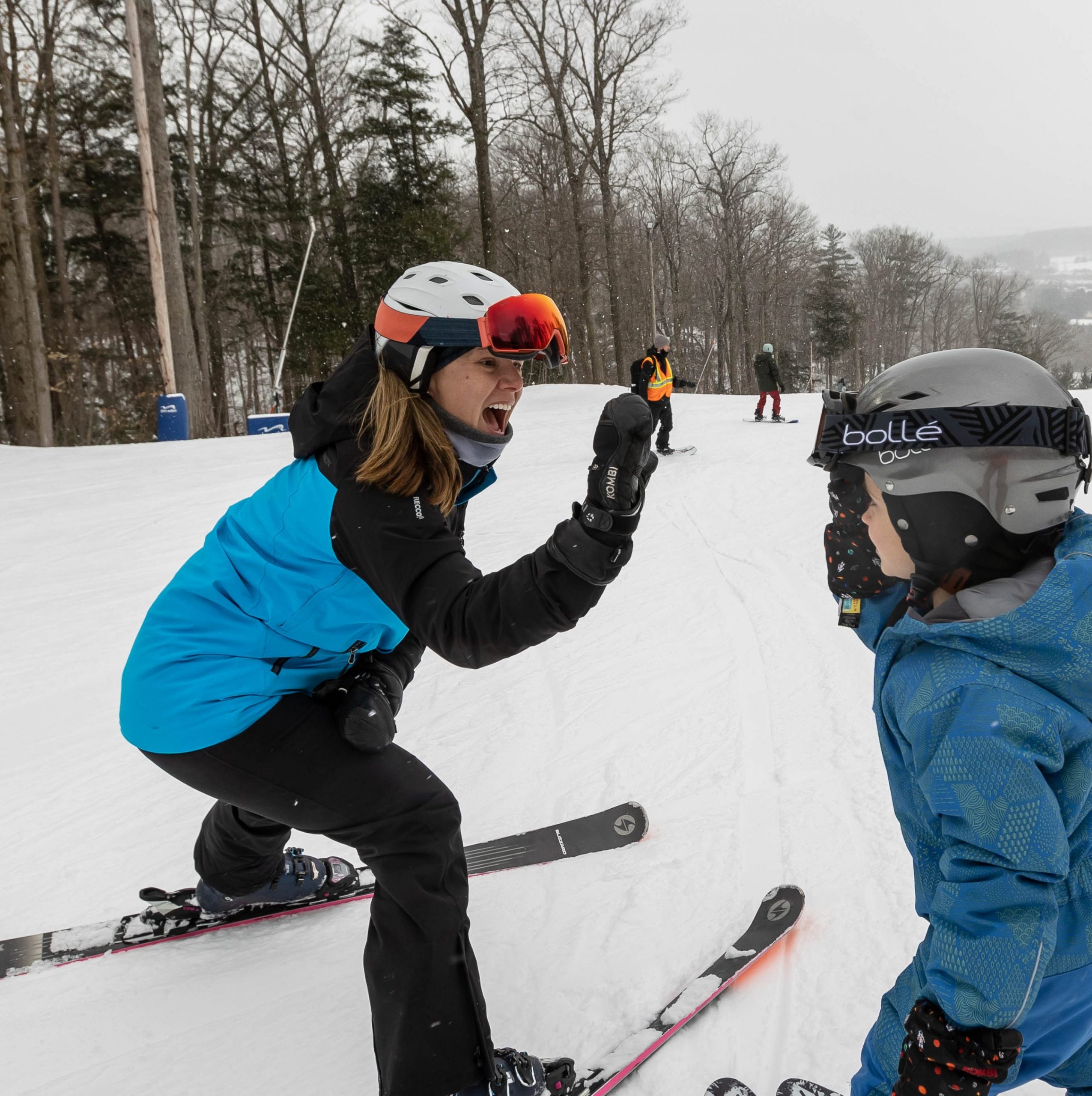 a young girl on skis gives a high-five to another young child