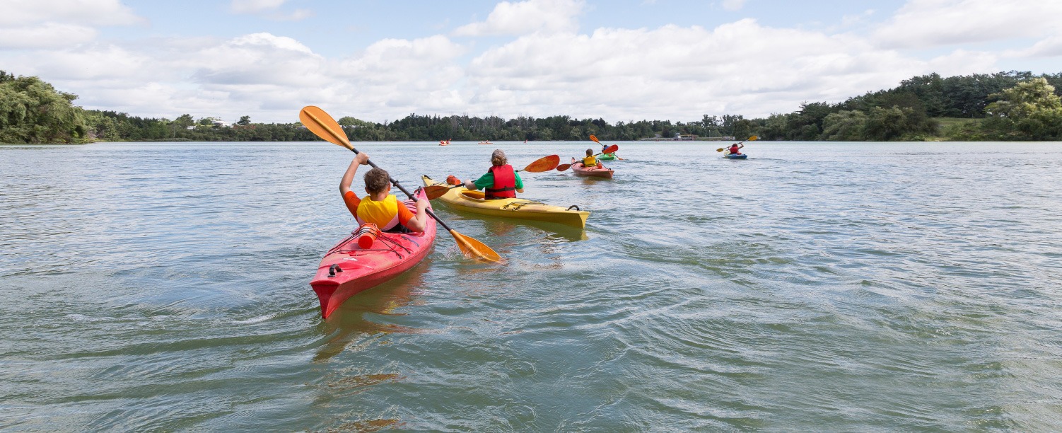 A group of children kayaking on a lake.