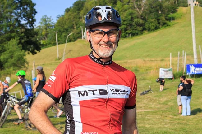 一个戴着自行车头盔、穿着赛车服的男人对着镜头微笑。