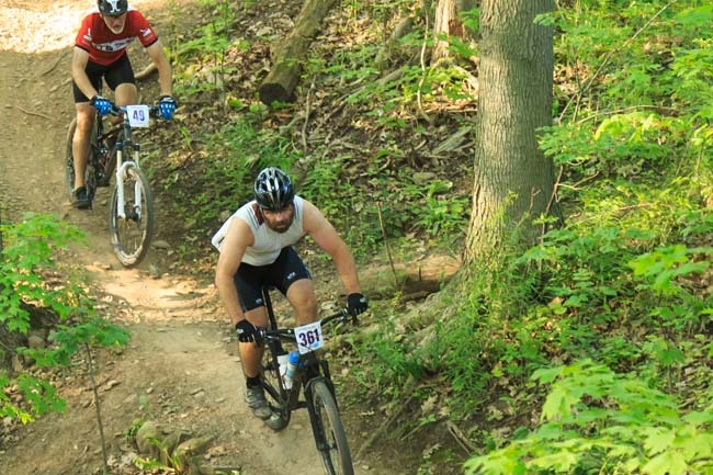 two mountain bikers ride down a trail in the forest