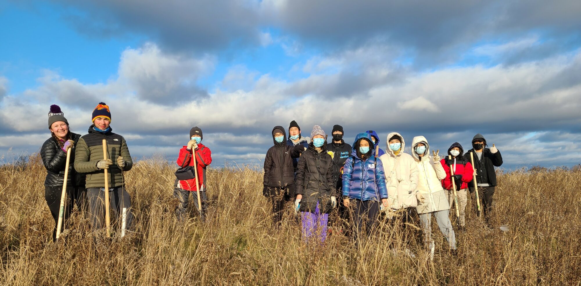 a group of people in winter jackets stand together in a field