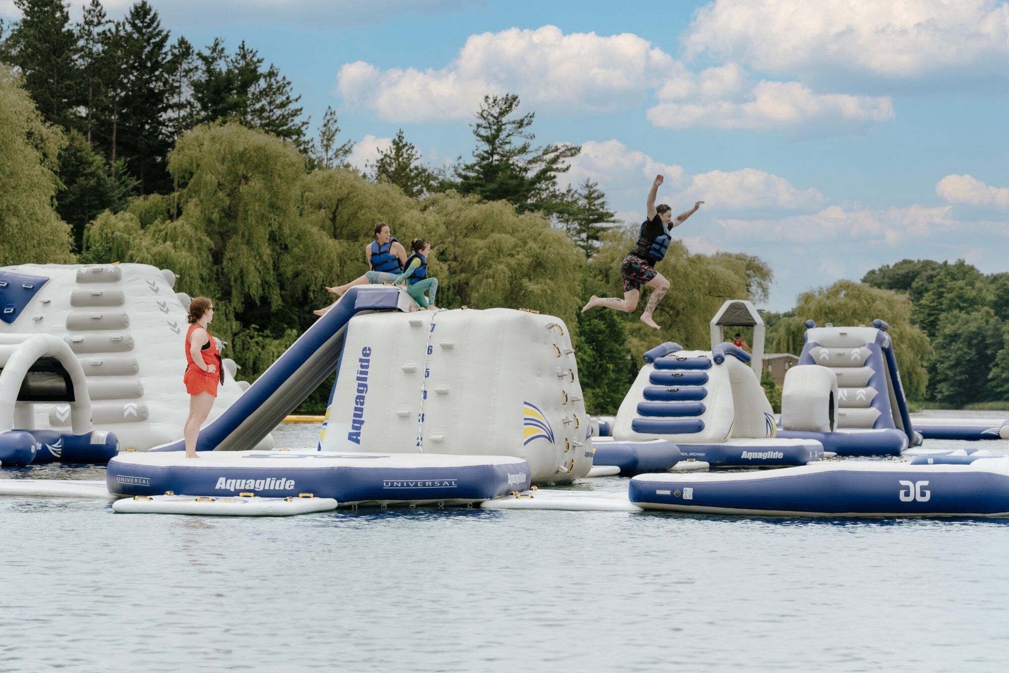 A group of individuals having fun at Kelso Cove Waterpark, with one person shown jumping off a taller feature