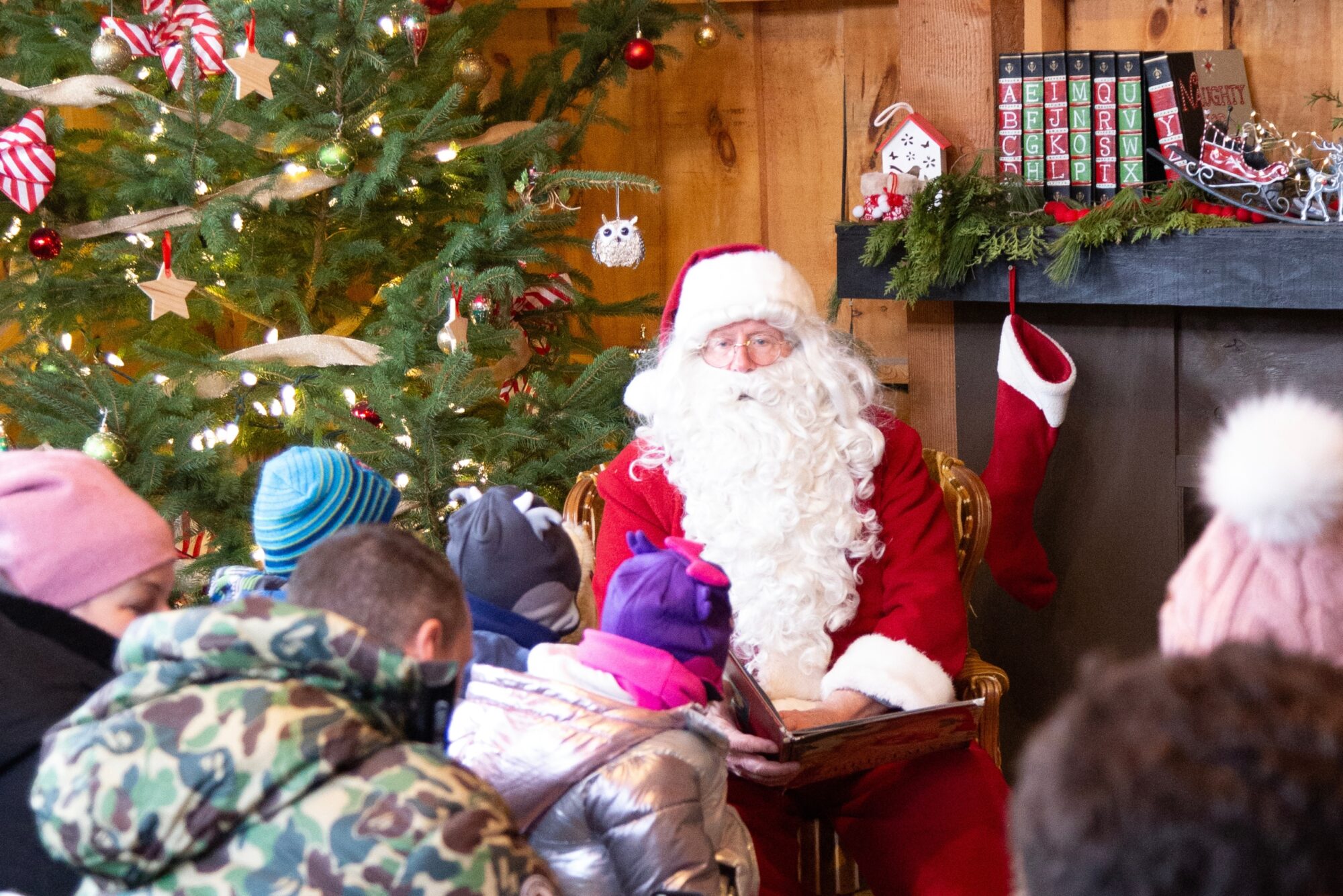 Santa reading a story to a group in a log cabin